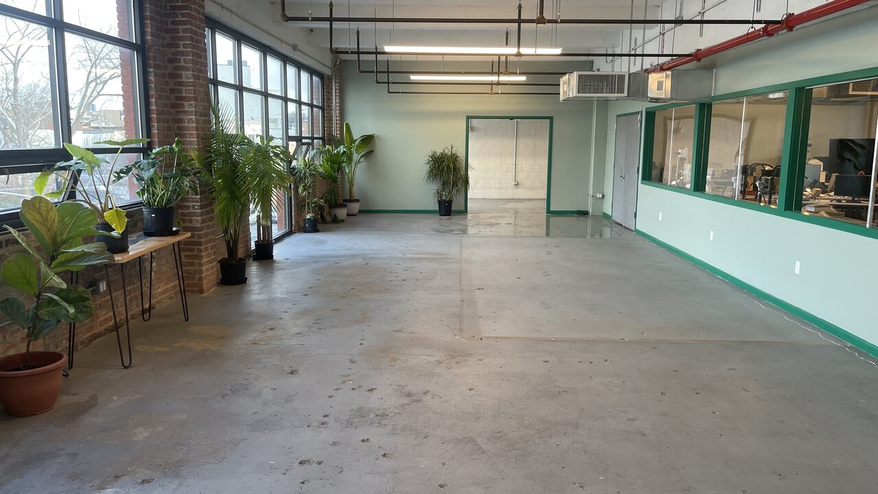 The Plant loft with potted plants and Manhattan skyline through the windows
